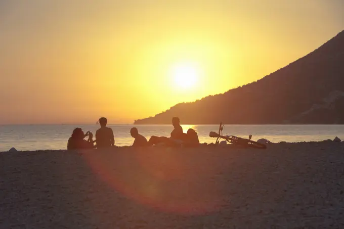 Small group of people watching sunset on beach, Vigan, Croatia