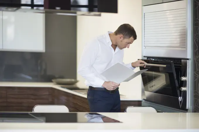 Mid adult man inspecting oven in kitchen showroom