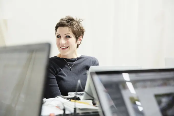 Businesswoman smiling while working at her computer in a modern office.