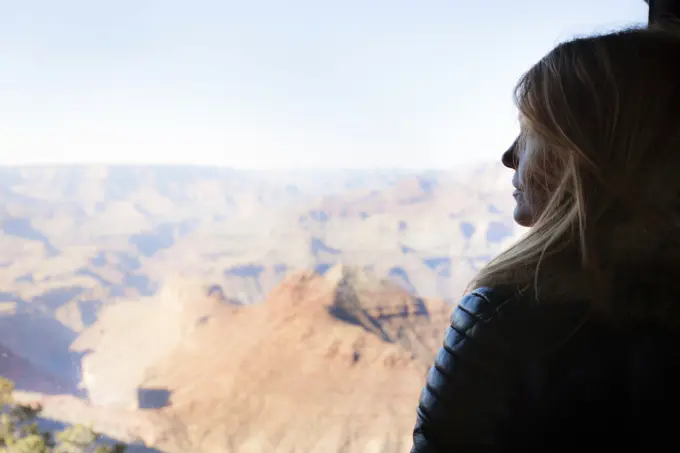 Woman gazing out over the Grand Canyon at sunrise