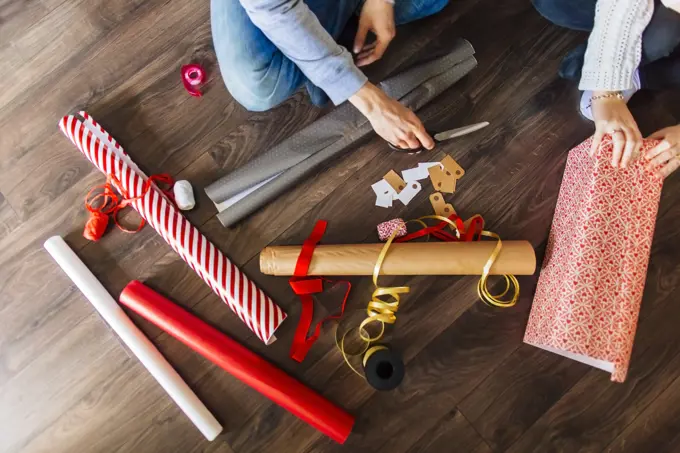 Busy hands wrap holiday gifts with festive paper and ribbon