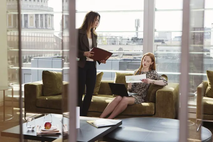 Two professionals discussing work in a modern office lounge.