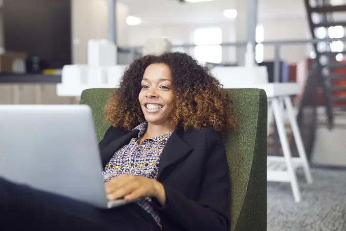 Smiling woman working on laptop in a modern office space