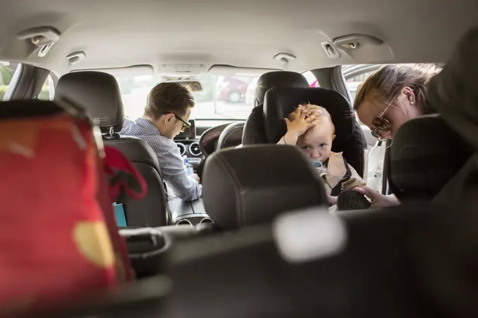 Family moment on a car ride with toddler looking curiously at the camera.