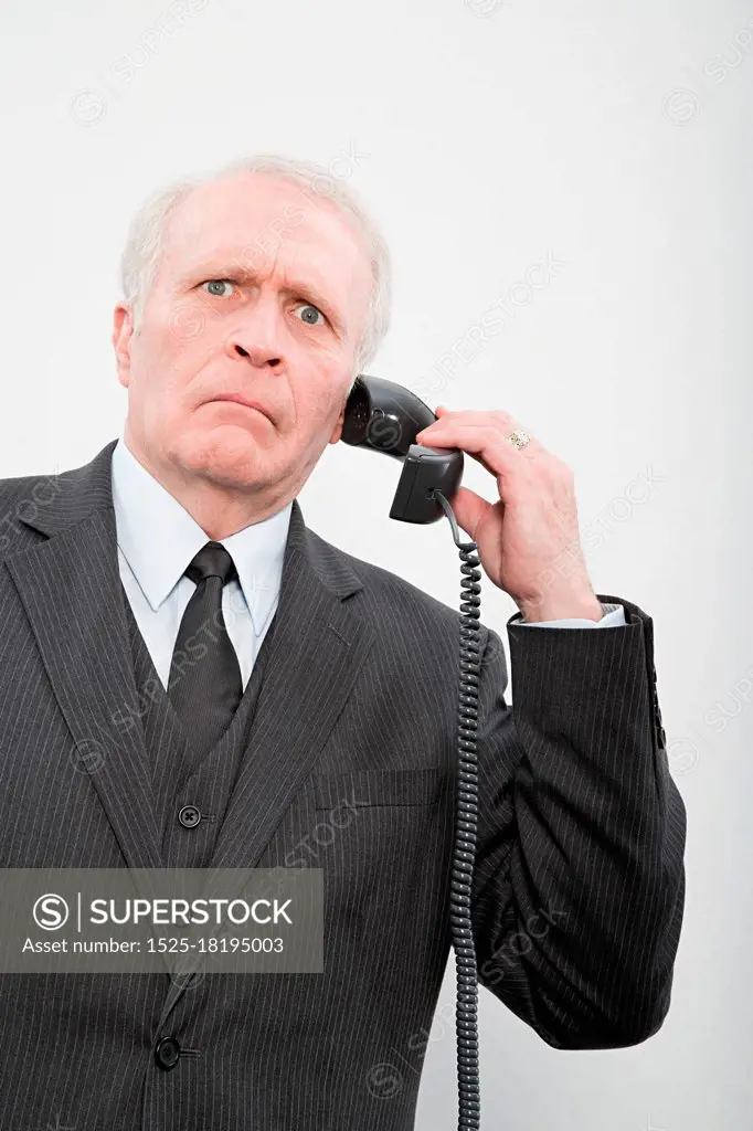 A confused businessman using a telephone