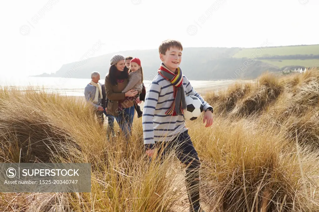 Multi Generation Family In Sand Dunes On Winter Beach