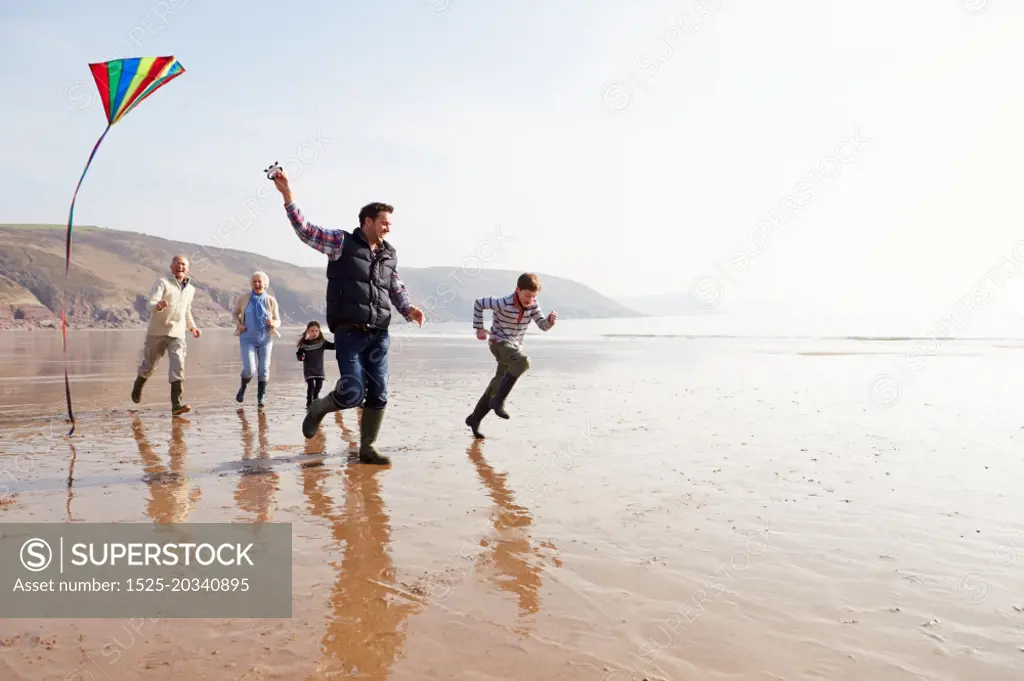 Multi Generation Family Flying Kite On Winter Beach