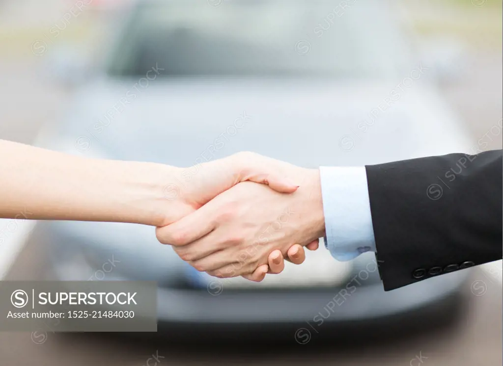 transportation, business, shopping and ownership concept - customer and salesman shaking hands outside