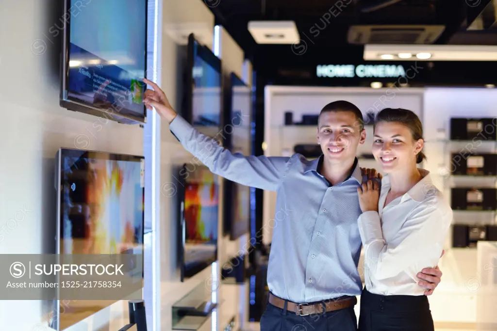 people in consumer electronics  retail store looking at latest laptop, television and photo camera to buy