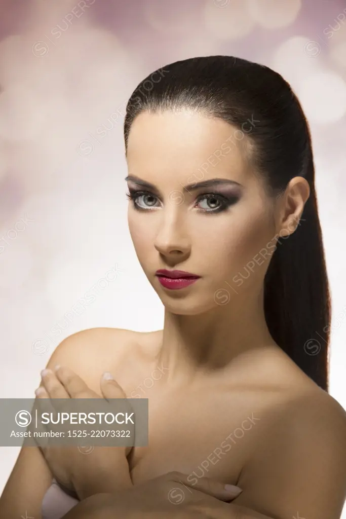 Short portrait of beautiful, young girl with long, straight, brown hair clipped in ponytail, looking in camera on color background&#xA;