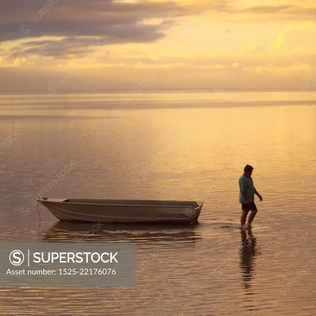 Man walking with boat in ocean at Moorea in Tahiti