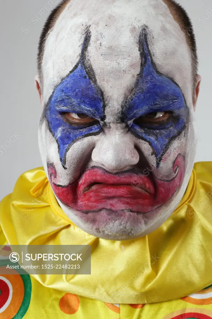 A nasty evil clown, angry and looking mean.