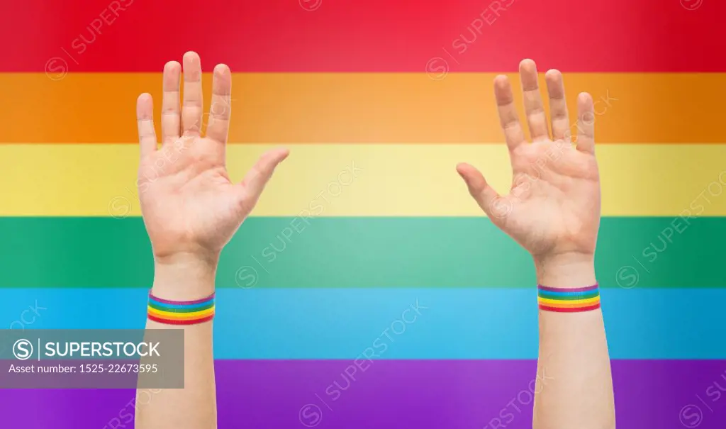 lgbt, same-sex relationships and homosexual concept - close up of male hands wearing gay pride awareness wristbands over rainbow colors background. hands with gay pride rainbow wristbands. hands with gay pride rainbow wristbands