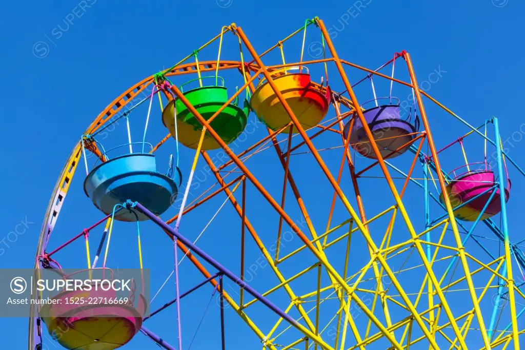 Scenic summer view of color Ferris observation wheel over blue sky in amusement park