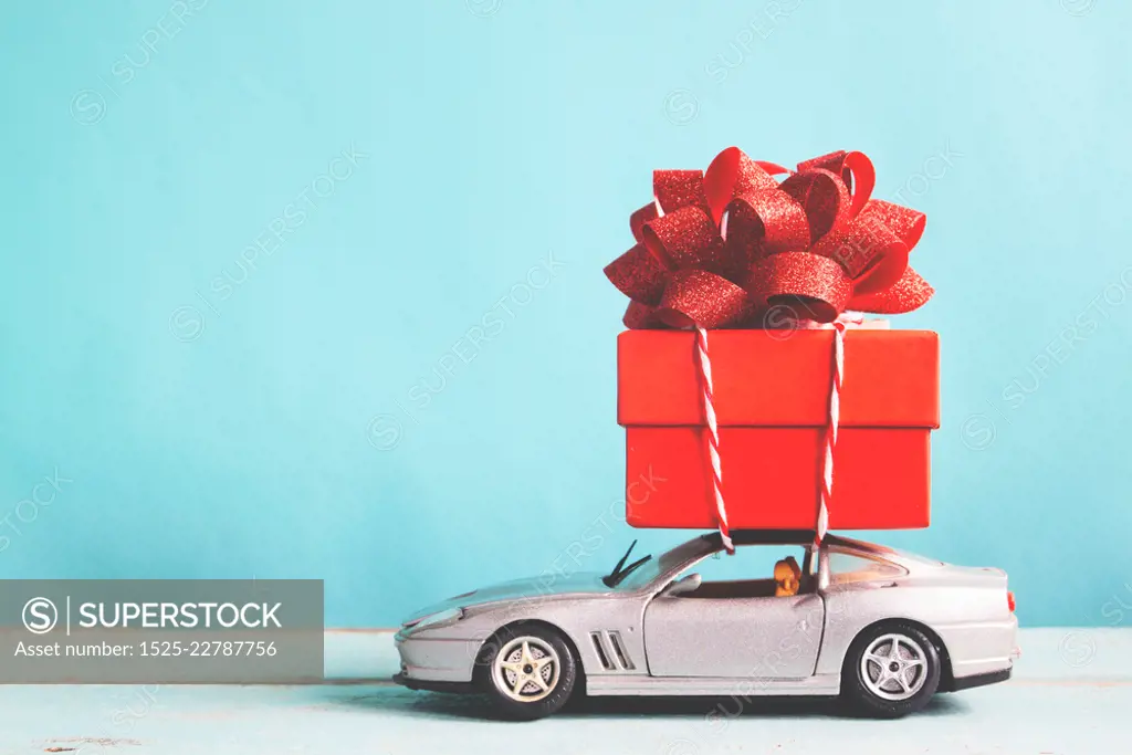 Red gift box on car toy with blue pastel color background, retro filter effect