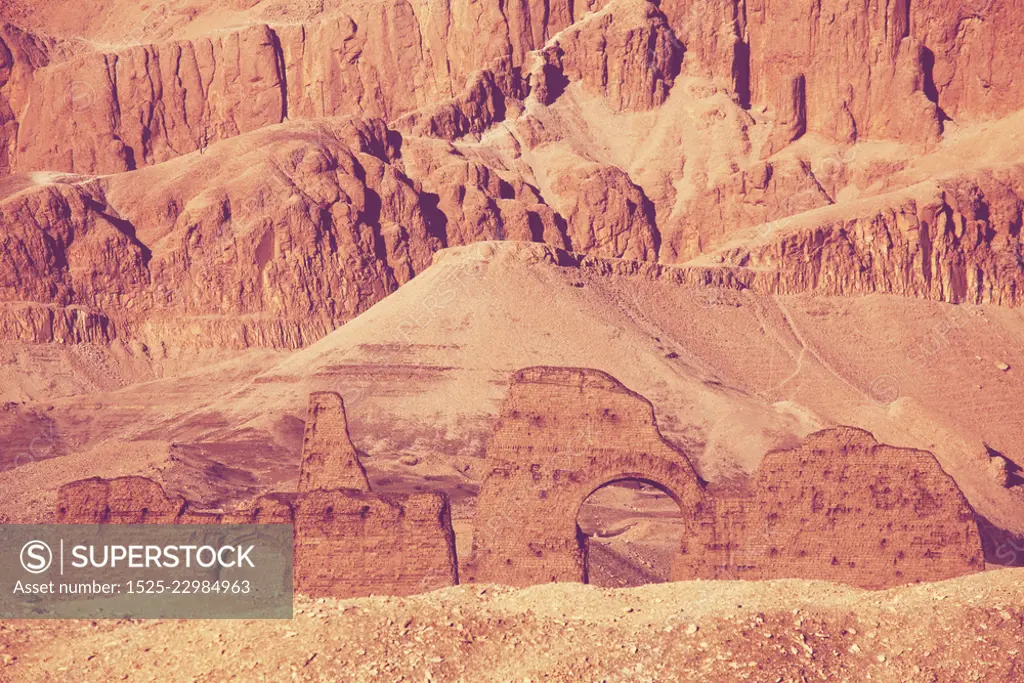 Unusual Egyptian landscapes. Dry mountains and anciend ruins toning in living coral color.