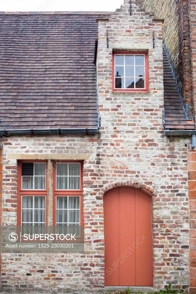 Painted door in a color of the year 2019 Living Coral Pantone on old European brick house of Bruges, Belgium.. Freshly painted door on old European stone house in a color of the year 2019 Living Coral Pantone.