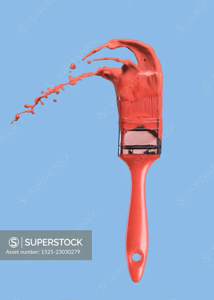 Splashes of paint and brush in color of the year 2019 Living Coral Pantone on a blue background. Place for text.. Paintbrush with liquid paint in a color of the year 2019 Living Coral Pantone in color isolated on a blue background.