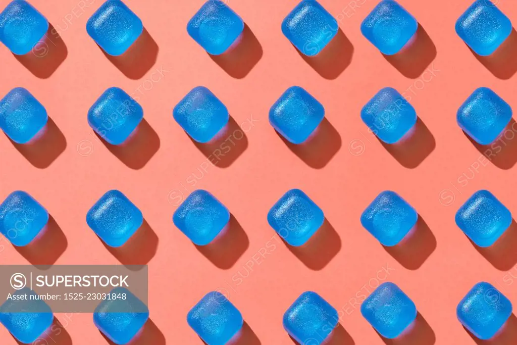 Blue plastic ice cubes pattern geometrical diagonal with hard shadows on a background in a color of the year 2019 Living Coral Pantone. Flat lay. Ceometrical pattern from blue plastic cubes with shadows on a background in a color of the year 2019 Living Coral Pantone. Top view.