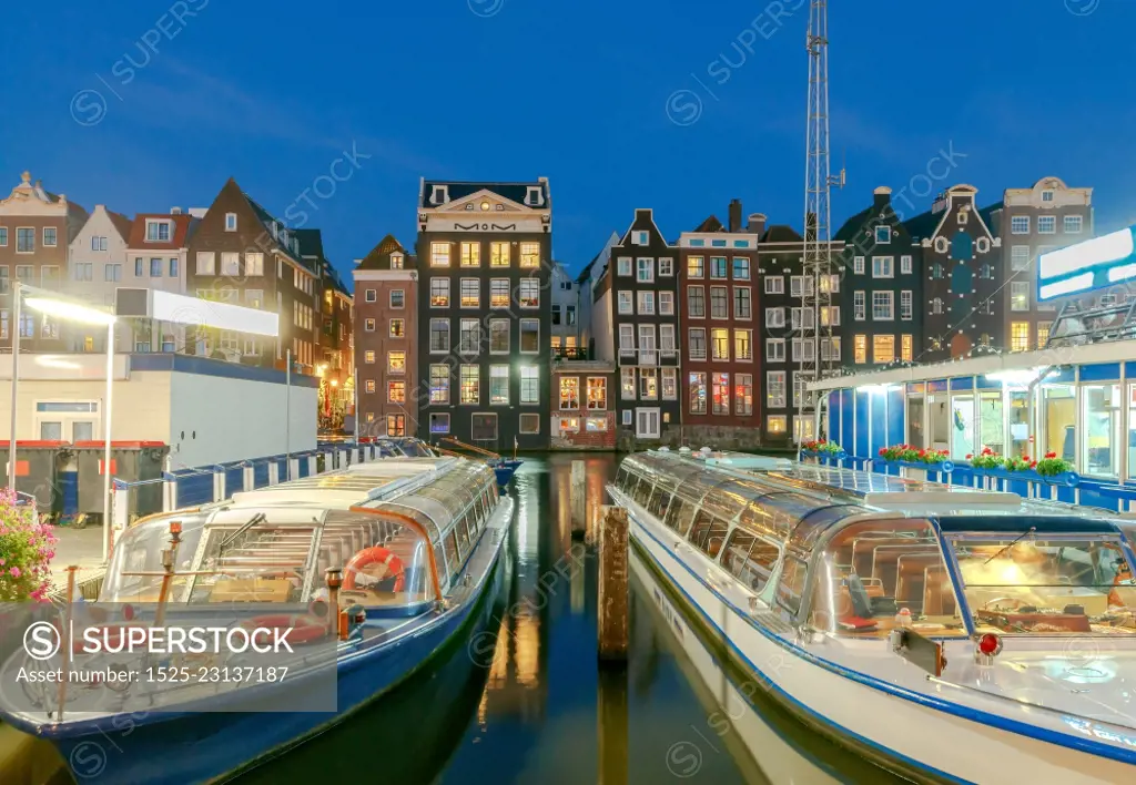 Facades of traditional Dutch houses on the canal in the night light. Amsterdam. Netherlands.. Amsterdam. Night view of the houses along the canal.