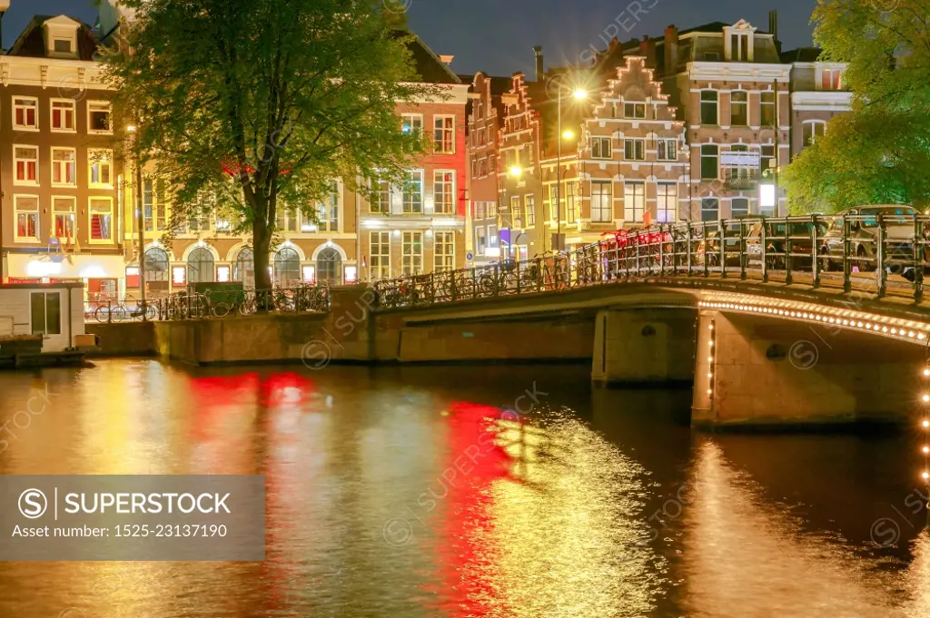 Amsterdam. Night view of the houses along the canal.. Facades of traditional Dutch houses on the canal in the night light. Amsterdam. Netherlands.