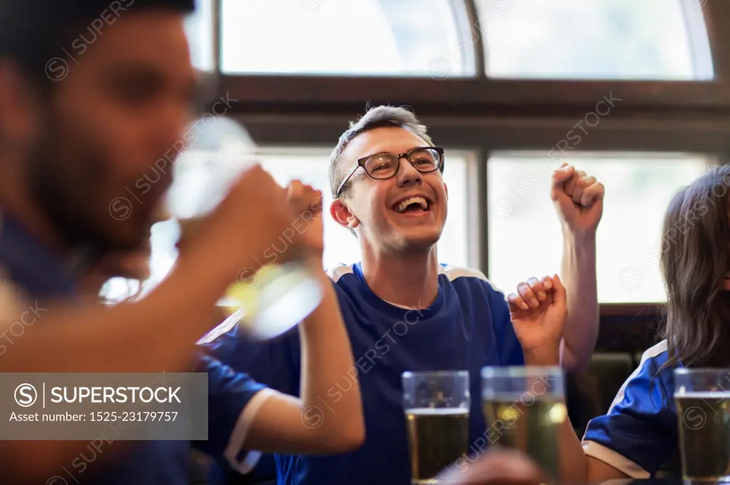 sport, people, leisure, friendship and entertainment concept - happy football fans or friends drinking beer and celebrating victory at bar or pub