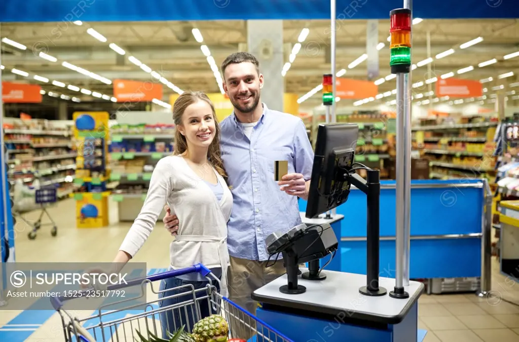 shopping, sale, payment, consumerism and people concept - happy couple with credit card buying food at grocery store or supermarket self-service cash register