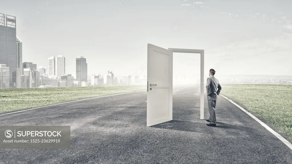 Door to new opportunity. Businessman standing in front of opened doors and making decision