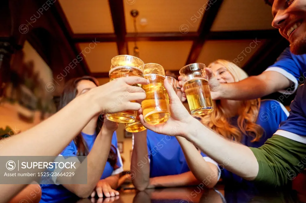 sport, soccer, people and leisure concept - happy friends or football fans clinking beer glasses at bar or pub. football fans clinking beer glasses at sport bar