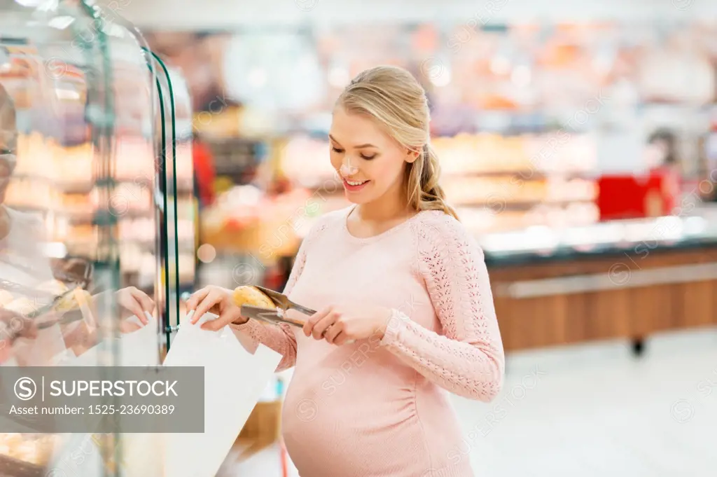 shopping, food, pregnancy and people concept - happy pregnant woman with paper bag and tongs buying buns at grocery store or supermarket. pregnant woman with bag buying buns at grocery