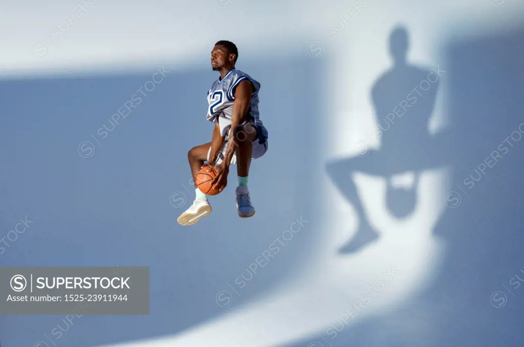 Basketball player with ball shows his skill in studio, high jump in action, neon background. Professional male baller in sportswear playing sport game, tall sportsman. Basketball player with ball, high jump in action