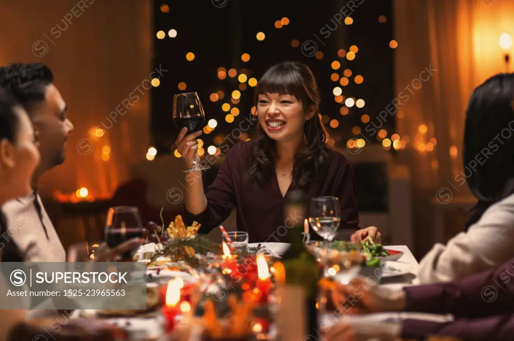 holidays, party and celebration concept - multiethnic group of happy friends having christmas dinner at home and drinking wine. happy friends drinking wine at christmas party