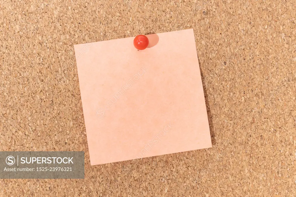 Blank note and push pin on cork board. Template to ad text or drawings