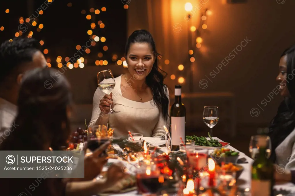 holidays, party and celebration concept - multiethnic group of happy friends having christmas dinner at home and drinking wine. happy friends drinking wine at christmas party