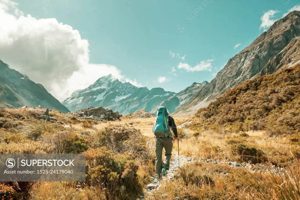 Man walking on hike trail route with Mount Cook National Park, beautiful mountains region. Tramping, hiking, travel in New Zealand.