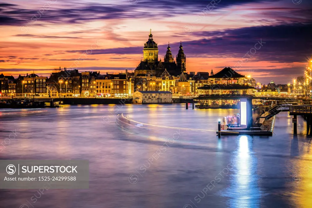 Amsterdam, Netherlands, Holland - December 2019: Pleasure boat on the city&rsquo;s water channels. river IJ. View over the skyline of Amsterdam during sunset 