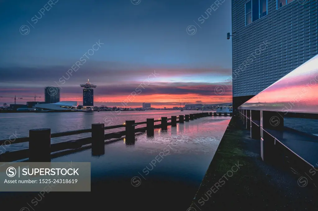 Impressive red cloud sky in the morning above the city of Amsterdam. View over &rsquo;the IJ&rsquo; lake near Amsterdam during the sunrise