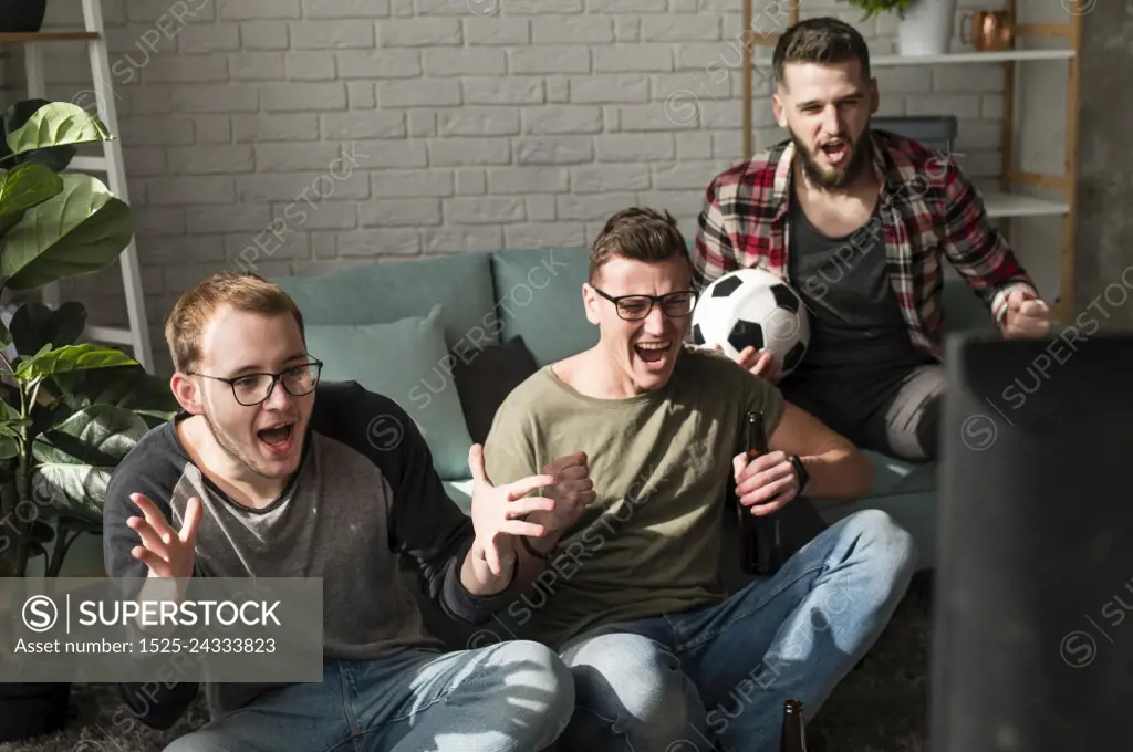 cheerful male friends watching sports tv with football