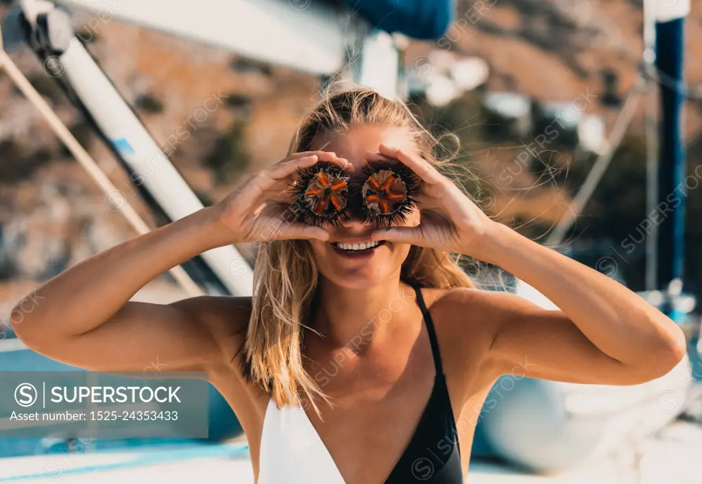 Portrait of a Cute Happy Girl Having Fun. Holding Two Half of a Sea Urchin on Eyes. Laughing and Enjoying Summer Trip on a Sailboat in Greece.. Happy Summer Vacation Concept