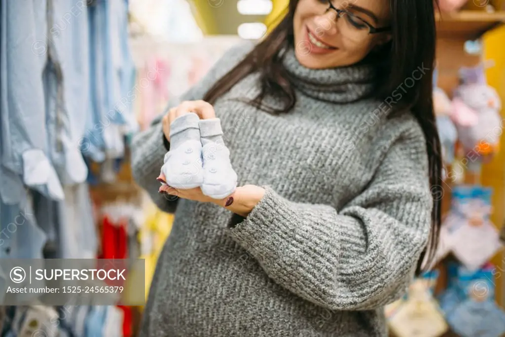 Happy future mother buys childrens clothes in the store for newborns. Pregnant woman in shop of goods for infants. Happy future mother buys childrens clothes