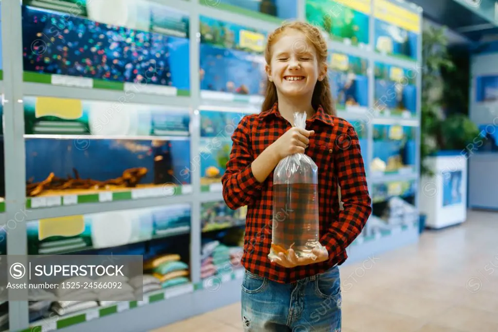 Happy little girl holds goldfish and makes a wish, pet store. Child buying equipment in petshop, accessories for domestic animals. Girl holds goldfish and makes a wish, pet store