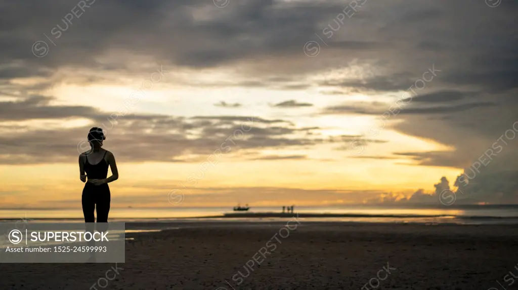 Woman in sportswear jogging on beach in the morning.