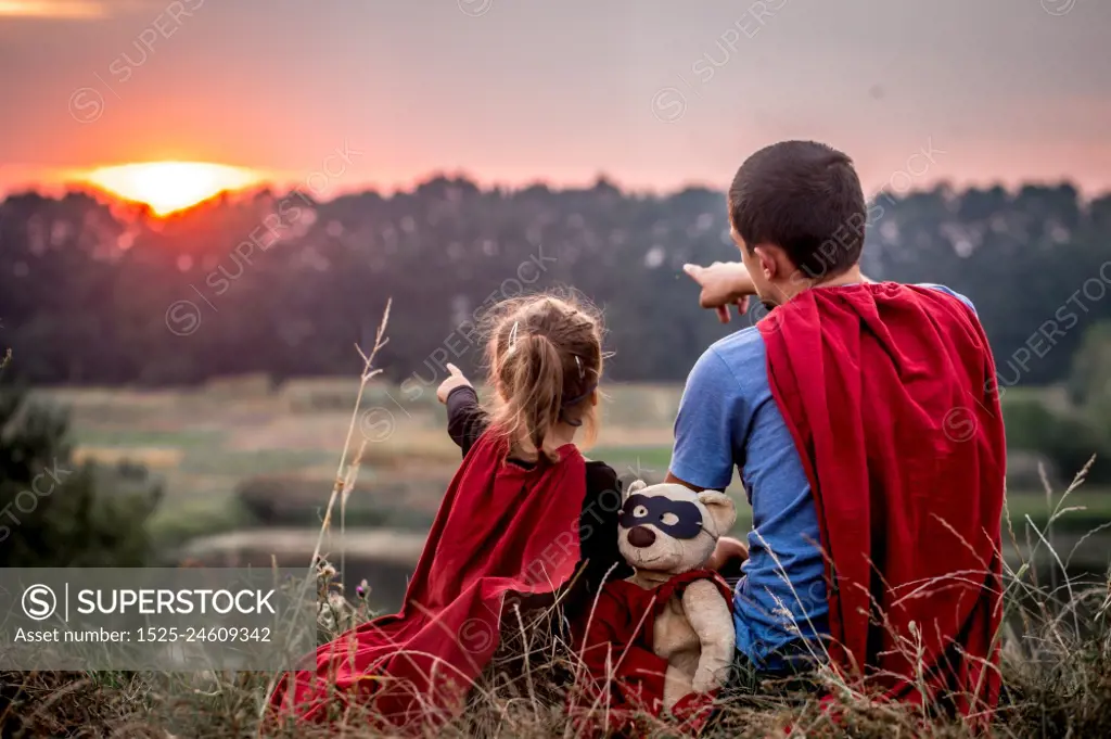 little girl with dad dressed in super heroes, happy loving family, father and daughter playing outdoors, family values. little girl with dad dressed in super heroes, happy loving family