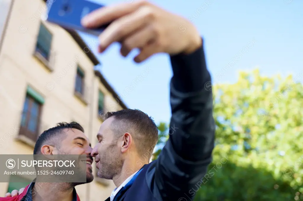 Gay couple making a selfie with their smartphone. Homosexual relationship concept.. Gay couple making a selfie with their smartphone.