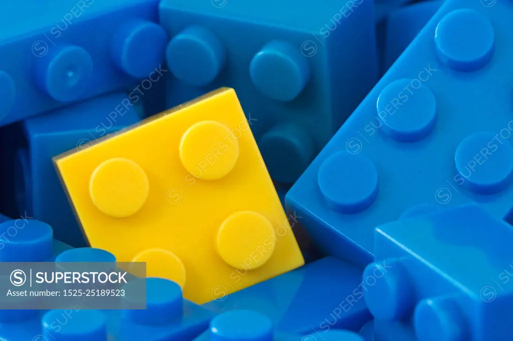 color toy background. yellow plastic brick in a middle of blue ones