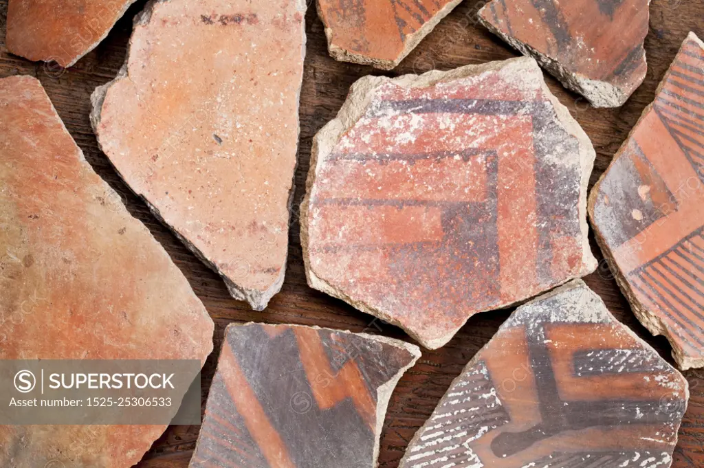 ancient Native American Indian (Anasazi) artifacts, several pottery fragments  on a wood background