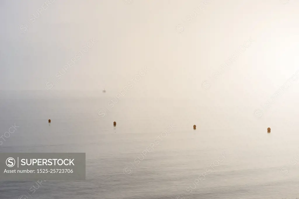 Minimalist fine art image of buoys at sea during foggy morning. Fine art minimalist image of buoys at sea during foggy morning