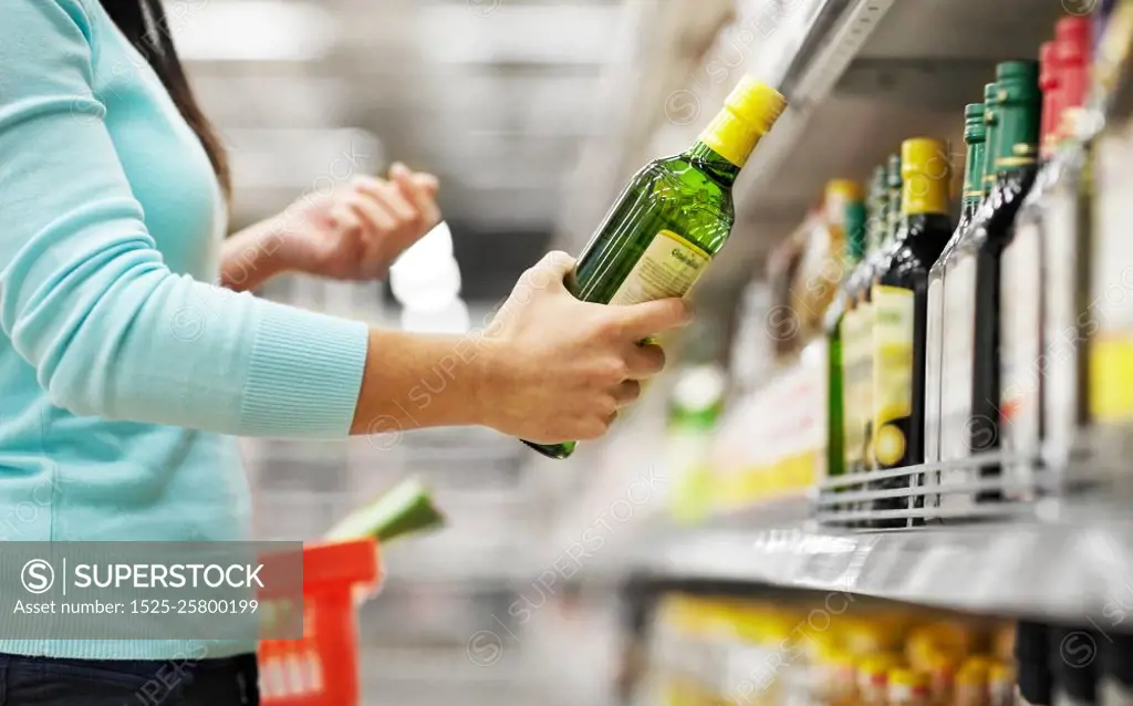 sale, shopping, food, consumerism and people concept - woman buying olive oil at grocery store or supermarket. woman buying olive oil at supermarket or grocery. woman buying olive oil at supermarket or grocery