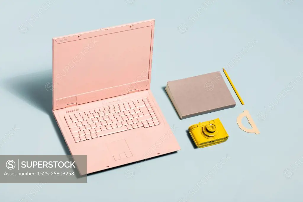 Minimal pastel workspace equipment. Pink laptop, yellow camera, notebook. Millennial lifestyle.. Minimal pastel workspace equipment.