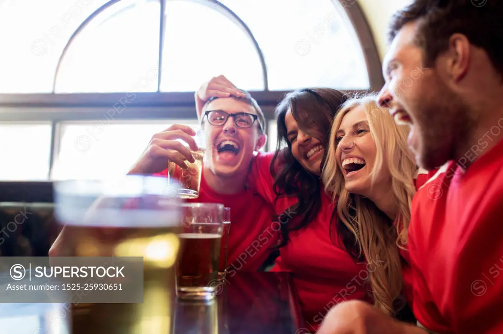 sport, people, leisure, friendship and entertainment concept - happy football fans or friends drinking beer and celebrating victory at bar or pub